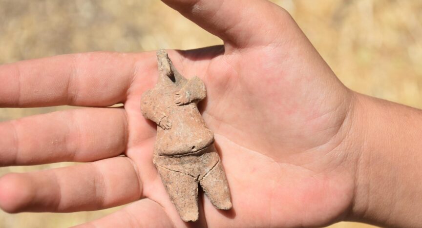 This 7,800-year-old female figurine found in Ulucak Mound, Izmir, Türkiye (DHA). The figure is on the palm of someone's hand, has a narrow pointy head and bulging stomach. Source: Daily Sabah