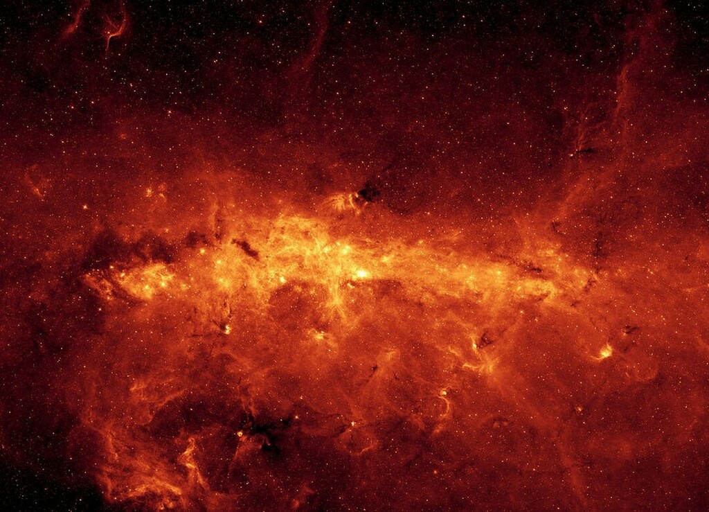 The Milky Way Galaxy in bright orange captured by the Spitzer Space Telescope in infrared.