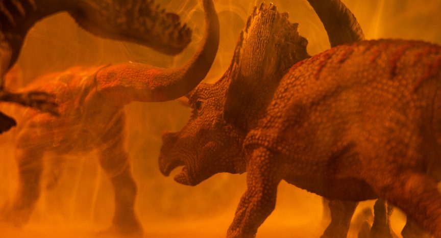 Some dinosaurs in bright orange light as if dust is being spread around